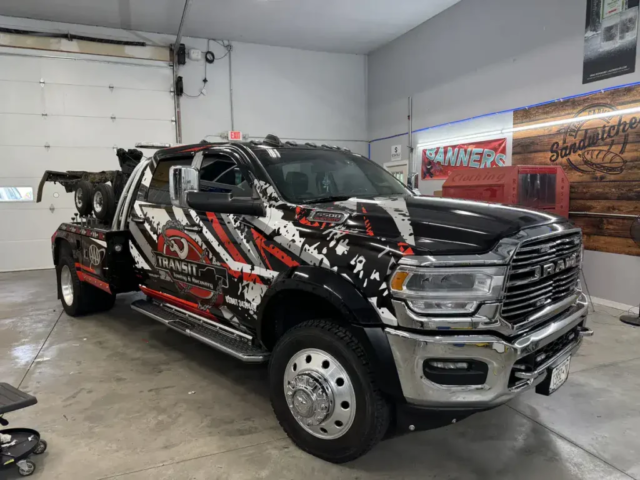 Ninja Graphics vinyl wrap for Transit Towing and Recovery tow truck parked inside a garage, showcasing intricate design and branding.