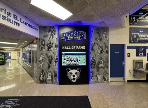 Daemen Athletics Hall of Fame display. The display has a black backdrop with a blue-lit “DAEMEN ATHLETICS” logo at the top.