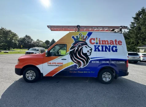 A Climate King HVAC service van with a colorful wrap design is parked in an outdoor lot. The wrap features a bold lion logo wearing a crown, along with the company’s name “Climate King” in red and blue text.